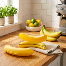 تحميل الصورة في عارض المعرض، Two inflatable banana-shaped objects on a wooden surface with a bottle and bag in the background.
