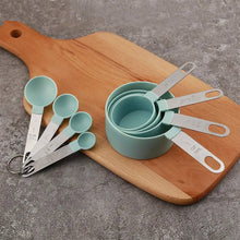 Load image into Gallery viewer, Set of measuring cups and spoons on a wooden cutting board with a gray concrete background
