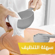 تحميل الصورة في عارض المعرض، Person cleaning a gray measuring cup with a white cloth on a wooden surface, with Arabic text indicating ease of cleaning.

