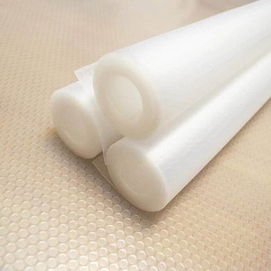 Two rolls of white non-slip shelf liner placed on a textured surface.