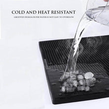 Load image into Gallery viewer, Black rubber mat with grooved design on a white background, showing water being poured onto ice cubes.
