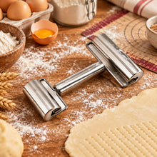 تحميل الصورة في عارض المعرض، A stainless steel pastry roller with a long handle lies on a wooden surface dusted with flour, surrounded by baking ingredients and rolled dough.
