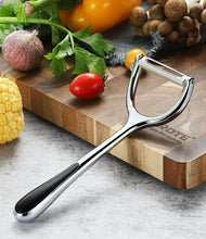 تحميل الصورة في عارض المعرض، Metal vegetable peeler on a wooden cutting board with vegetables in the background
