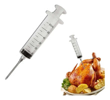 Load image into Gallery viewer, Two syringes being used to inject a roasted chicken with a plate of vegetables on a white background.
