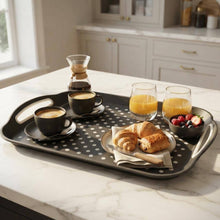 تحميل الصورة في عارض المعرض، A rectangular metal breakfast tray with cutout handles and a polka-dot pattern, styled on a white marble kitchen island with coffee, orange juice, croissants, and fruit.

