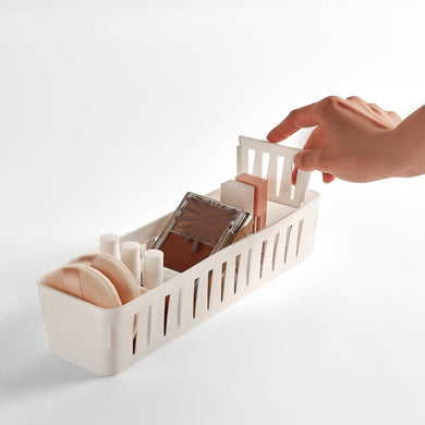 A plastic storage organizer with 5 adjustable compartments being manipulated by a hand to show the adjustable nature of the compartments.