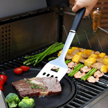 Load image into Gallery viewer, Person grilling steak and vegetables on a barbecue with a spatula.
