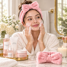 Load image into Gallery viewer, Woman wearing a pink bow headband beside skincare products
