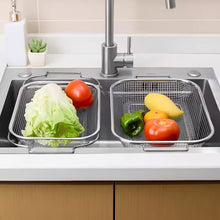 Load image into Gallery viewer, Two stainless steel mesh sink baskets holding fresh vegetables, placed in a modern kitchen sink with a faucet and countertop visible.
