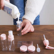 Load image into Gallery viewer, Person pouring liquid into a small bottle with various small containers and bottles on a wooden surface.
