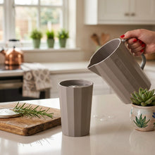 Load image into Gallery viewer, Gray kettle pouring water into a gray cup on a white surface with a blurred kitchen background.
