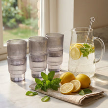 تحميل الصورة في عارض المعرض، Set of six ribbed glass tumblers on a textured surface with decorative elements in the background.

