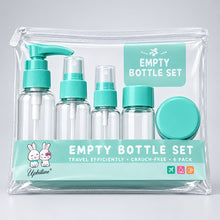 Load image into Gallery viewer, An empty bottle set in a clear zippered plastic bag, containing four small clear bottles with turquoise caps and pump/spray tops, plus a round turquoise lid, photographed on a light wood surface.
