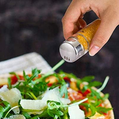 Hand sprinkling seasoning from a pepper grinder onto a salad.