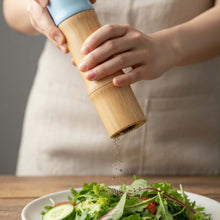 تحميل الصورة في عارض المعرض، Person seasoning a salad with a wooden pepper grinder.
