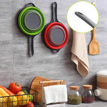 تحميل الصورة في عارض المعرض، Collapsible colanders in green and red hanging on a wall with kitchen utensils and ingredients below.
