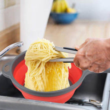 تحميل الصورة في عارض المعرض، Person using tongs to transfer cooked spaghetti from a red and gray colander into a sink.
