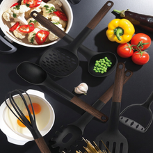 تحميل الصورة في عارض المعرض، Set of black and wooden kitchen utensils on a black surface with vegetables and food items.
