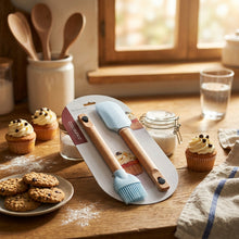 تحميل الصورة في عارض المعرض، Two silicone spatulas with wooden handles on a gray placemat with a wicker border.

