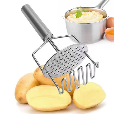 A stainless steel potato masher with a double press mechanism, alongside raw potatoes and a small bowl of mashed potatoes.