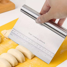 Load image into Gallery viewer, A stainless steel dough scraper with a ruler printed on the blade, being held by a hand over a yellow cutting board with dough pieces.
