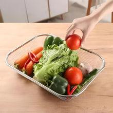 تحميل الصورة في عارض المعرض، A rectangular stainless steel mesh vegetable basket on a light wood table, filled with fresh vegetables like lettuce, tomatoes, carrots, and peppers, with a hand placing a tomato into the basket.
