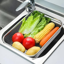 تحميل الصورة في عارض المعرض، A stainless steel sink basket with a mesh bottom, shown in a kitchen sink filled with vegetables including lettuce, tomatoes, corn, carrots, and potatoes.
