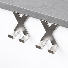 Load image into Gallery viewer, Two metallic X-shaped under-cabinet hooks mounted on a white cabinet below a gray countertop.
