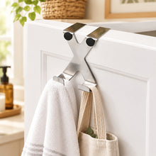 Load image into Gallery viewer, A stainless steel X-shaped wall hook with two mounting plates and two hanging hooks, shown mounted on a white wall.
