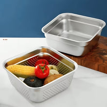 Load image into Gallery viewer, Two square stainless steel colanders, one empty and one filled with vegetables including corn, a tomato, a zucchini, and a potato, displayed on a white surface with a wooden cutting board and a blue background.
