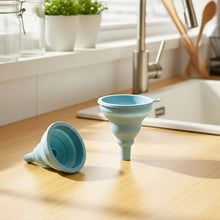 Load image into Gallery viewer, Two blue silicone funnels on a kitchen counter with a sink and window in the background.
