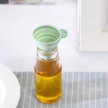 Load image into Gallery viewer, Collapsible green funnel over a glass bottle of oil on a kitchen counter.
