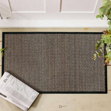 تحميل الصورة في عارض المعرض، Black doormat on a wooden floor with a newspaper and plant in the foreground.
