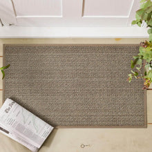 تحميل الصورة في عارض المعرض، Textured doormat on a wooden floor with a newspaper and plant.
