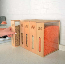 Load image into Gallery viewer, Four wooden spice jars with clear front panels and engraved labels, filled with brown, beige, orange-red, and white spices, arranged on a kitchen counter with a hand reaching in to adjust the leftmost jar.
