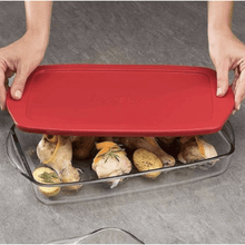 تحميل الصورة في عارض المعرض، Hands placing a red plastic lid on a heat-resistant glass baking tray with chicken and vegetables inside.

