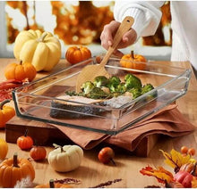 تحميل الصورة في عارض المعرض، Person stirring baked salmon and broccoli in a heat-resistant glass tray, surrounded by pumpkins and fall decor.
