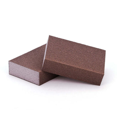 Two brown carborundum cleaning sponges of different sizes placed on a white background.