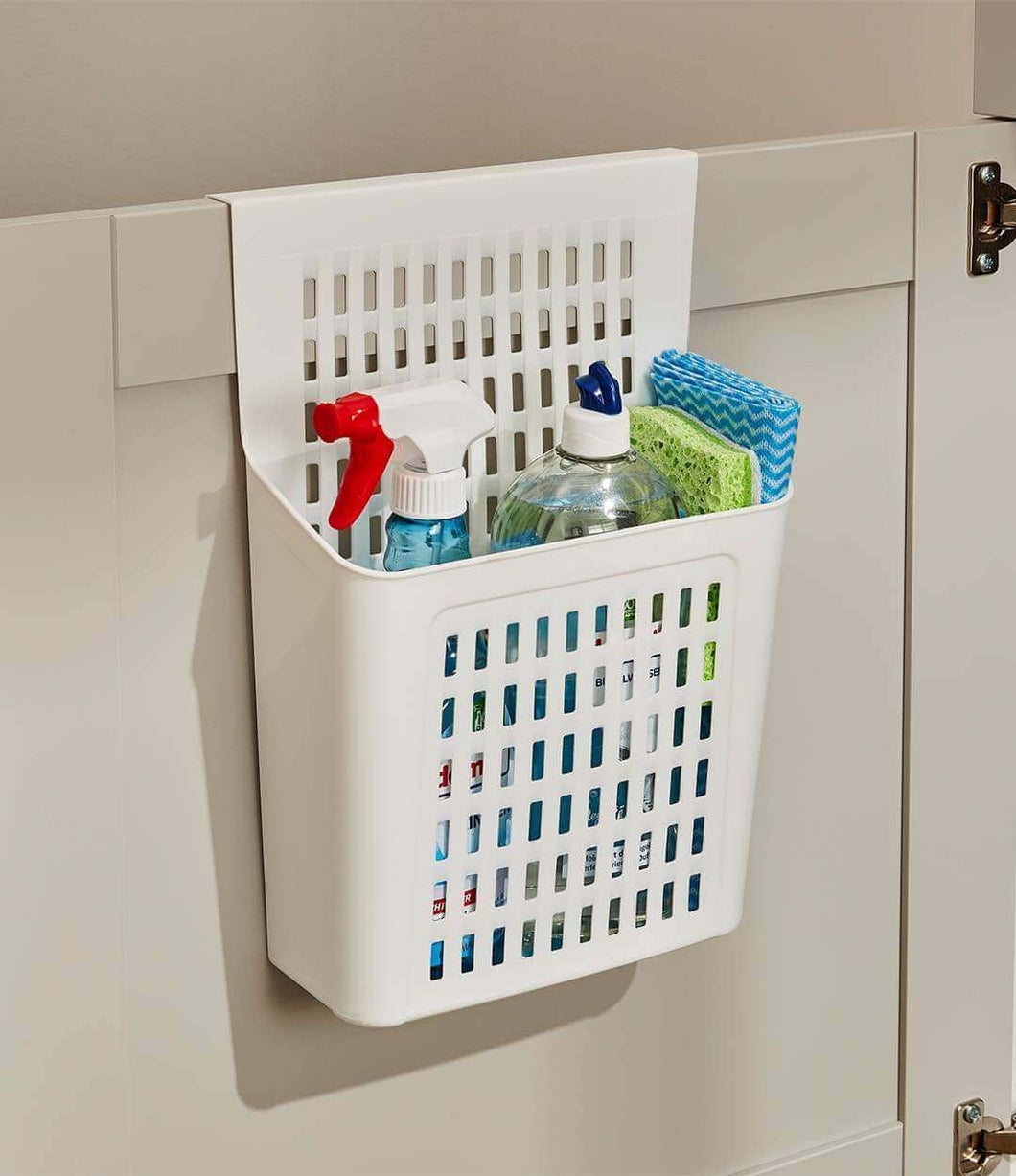 A white hanging organizer with a grid-like design, attached to a cabinet door, containing various cleaning supplies.