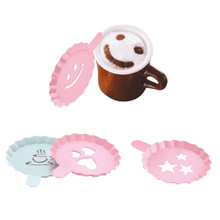 Load image into Gallery viewer, A set of plastic stencils in beige, pink, and dark grey, with one stencil depicting a smiling face, another resembling a star, and others with various patterns, alongside a cup of cappuccino with a decorative pattern on the cup.
